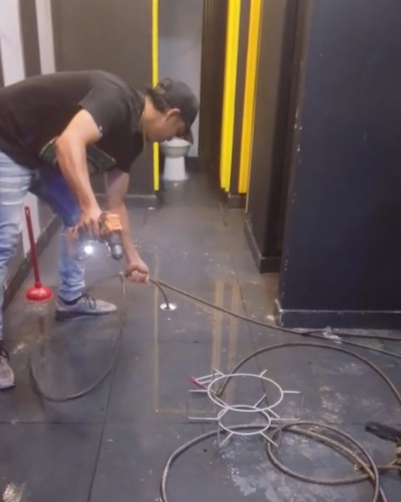 Técnico realizando el destape de un desagüe de piso